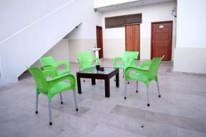 Seasons Inn في كراتشي: غرفة بها كراسي خضراء وطاولة ودرج