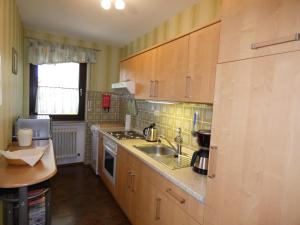 a small kitchen with wooden cabinets and a sink at Ferienwohnung Neumann in Gersfeld