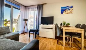 a living room with a desk with a tv and a table with chairs at Apartament Atlantycki in Jastrzębia Góra