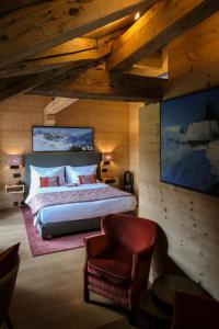a bedroom with a large bed and a chair at Hotel-Restaurant Valrose in Gstaad
