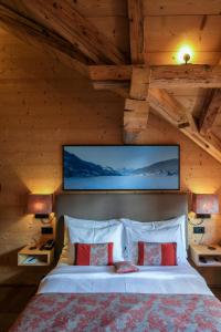 a bedroom with a large bed with a tv on the wall at Hotel-Restaurant Valrose in Gstaad