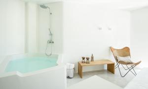 a white bathroom with a tub and a chair at Althea Traditional Hotel in Alonnisos Old Town