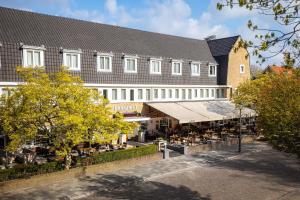 a large building with tables and chairs in front of it at Hotel Parkzicht Eindhoven in Eindhoven