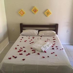 Una cama con pétalos de rosa roja. en Pousada Capyvara en Arenápolis