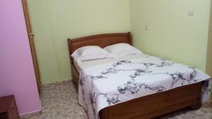 a small bedroom with a bed with white sheets and pillows at Maison Rose in Douala