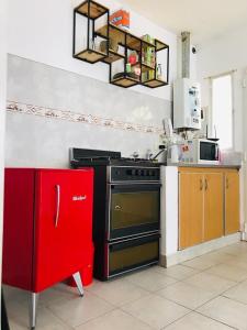 a kitchen with a stove and a red refrigerator at Excelente Ubicación con Patio y Parrilla Departamento Luminoso y con Desayuno in Junín