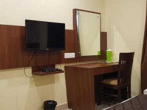 a room with a desk with a television and a mirror at Hotel ParkwayInn in Kelambākkam