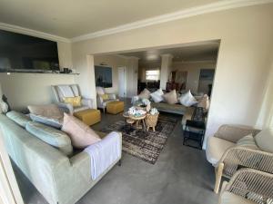 a living room with couches and a table at Lasalle holiday home (Sun, Beach, Views, Fun for everyone!) in Plettenberg Bay
