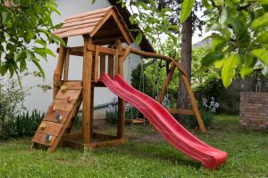 un parque infantil de madera con un tobogán y una torre en Árnyas vendégház, Füge apartman en Balatonboglár