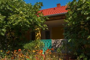 una pequeña casa con una puerta azul y flores en Árnyas vendégház, Füge apartman en Balatonboglár