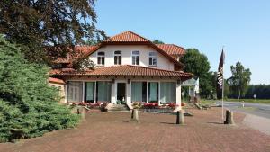 een huis met een vlag ervoor bij Hotel Restaurant Am Pfauenhof in Quakenbrück