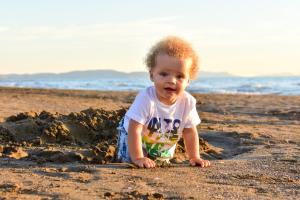 a baby playing in the sand on the beach at Canado Club Family Village in Marina di Castagneto Carducci