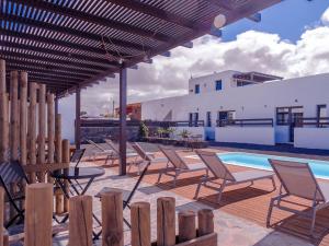 a group of chairs and a pool with a pergola at MAAR House Lajares in Lajares