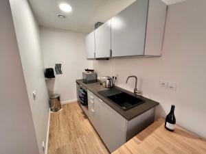 małą kuchnię z białymi szafkami i zlewem w obiekcie Appartements calmes - Standing - Hypercentre - CLIM - WIFI - Netflix w Montpellier