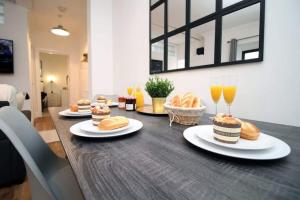 una mesa con platos de bollería y vasos de zumo de naranja en Penarth/Cardiff Bay: Deluxe Flat: 10 Mins to City!, en Cardiff