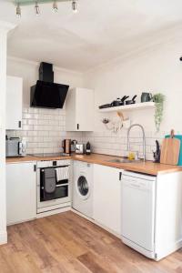 a kitchen with white cabinets and a washer and dryer at Penarth/Cardiff Bay: Deluxe Flat: 10 Mins to City! in Cardiff
