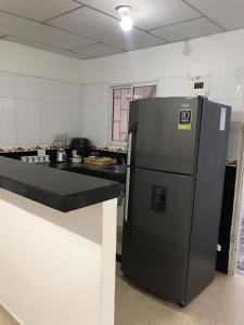una cocina con nevera negra junto a un mostrador en Apartamento Cómodo, en Ríohacha
