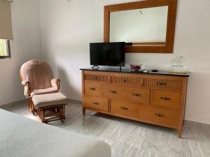 a bedroom with a dresser with a television and a chair at Closetoairport in Cancún