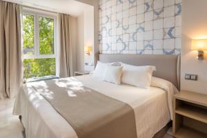 a hotel room with a large bed and a large window at Hotel San Pablo Sevilla in Seville