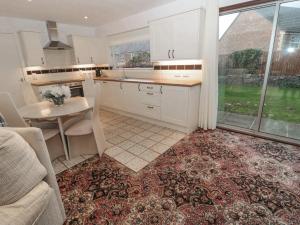 a kitchen with white cabinets and a table and a dining room at Garden House in Wooler