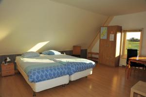 Schlafzimmer mit einem Bett, einem Schreibtisch und einem Fenster in der Unterkunft Witte Weelde Texel in De Koog