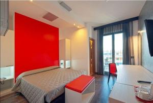 a bedroom with a red wall and a bed and a desk at Eden Hotel in San Salvo +11 photos