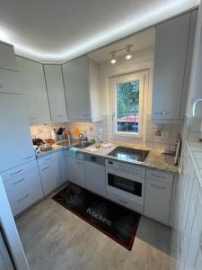 eine Küche mit weißen Schränken, einem Waschbecken und einem Fenster in der Unterkunft Ascona Casa Cristina in Ascona