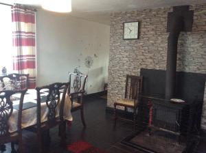 a living room with a fireplace and a table and chairs at Y Gerddi in Penmaen-mawr