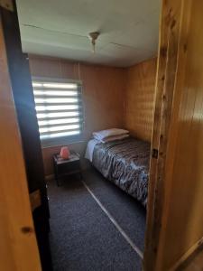 Un dormitorio pequeño con una cama y una ventana. en Cabaña Valle encantado, en Ancud