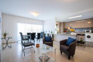 a living room with chairs and a table and a kitchen at Great 2 Bedroom apartment in Santa Luzia Tavira in Santa Luzia