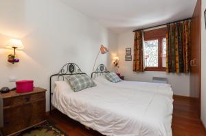 um quarto com uma cama branca e uma janela em Apartament Terrasses F em El Tarter