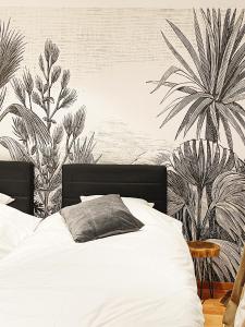 a bedroom with a white bed with a mural of palm trees at Le Pact - Gîte familial in Anhée