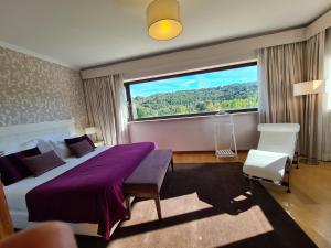 ein Schlafzimmer mit einem Bett und einem großen Fenster in der Unterkunft Quinta de Santo Estêvão Hotel Rural in Aguiar da Beira