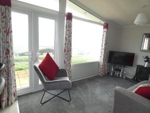 a living room with a chair and a television at Lodge 54 Elmrise Park in Llanstephan +2 photos