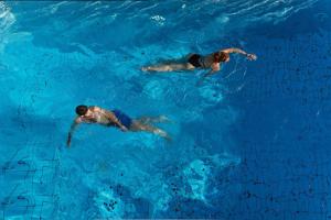 two people swimming in a pool of blue water at Erato Hotel in Agia Marina Aegina