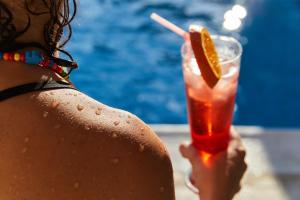 a woman holding a drink with an orange slice at Erato Hotel in Agia Marina Aegina