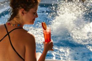 a woman in a bikini holding a drink at Erato Hotel in Agia Marina Aegina