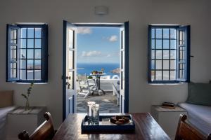 a living room with a table and a view of the ocean at Heliotopos in Imerovigli