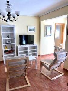 uma sala de estar com duas cadeiras e uma televisão em Playa y tranquilidad en El Portil em El Portil