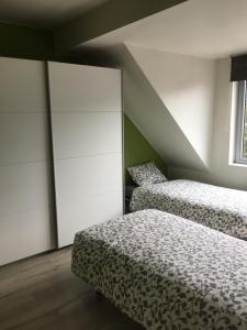 a bedroom with two beds and a closet at Duplex appartement in rustige woonwijk in Mortsel +7 photos