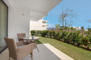 een patio met een tafel, stoelen en gras bij Luxury Apartment Leticia in La Cala de Mijas