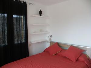 Schlafzimmer mit einem Bett mit roter Bettwäsche und einem Fenster in der Unterkunft Apartamento Caballito de Mar in L'Estartit