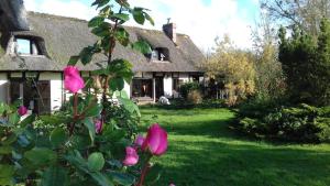 una casa con flores rosas delante de ella en Les 2 chaumières avec piscine en Épinay