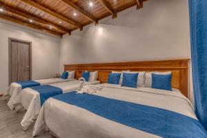 three beds in a room with blue and white at Swans Cay Hotel in Bocas del Toro +60 photos
