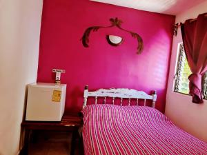 Un dormitorio con una pared de color rosa con una cama y una ventana en hotel playa del carmen en Playa del Carmen