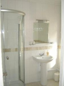 a white bathroom with a sink and a shower at Leverton House in Cambridge