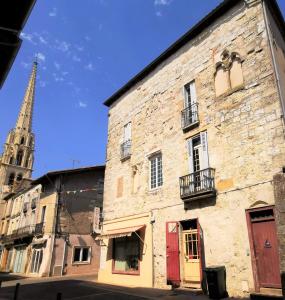 ein altes Steingebäude mit einer Kirche im Hintergrund in der Unterkunft Maison de caractère dans la bastide foyenne in Sainte-Foy-la-Grande