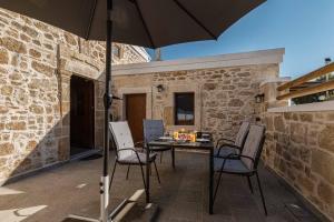 patio ze stołem, krzesłami i parasolem w obiekcie La casa dell'arch w mieście Charaki
