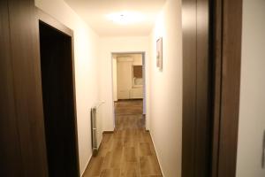 Čaglin的住宿－Green Gold，走廊通往带白色墙壁和木地板的客房