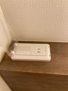 un teléfono celular sentado en un estante en una pared en BEE-HIVE巣鴨(Sugamo)【男性専用・Male Only】 en Tokio